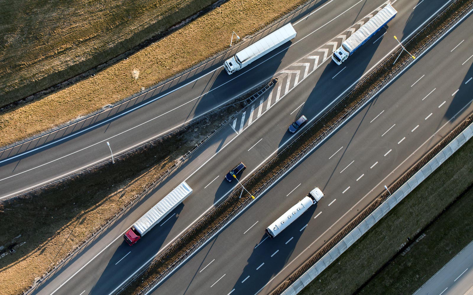Aerial view of four freight trucks on a highway and off-ramp