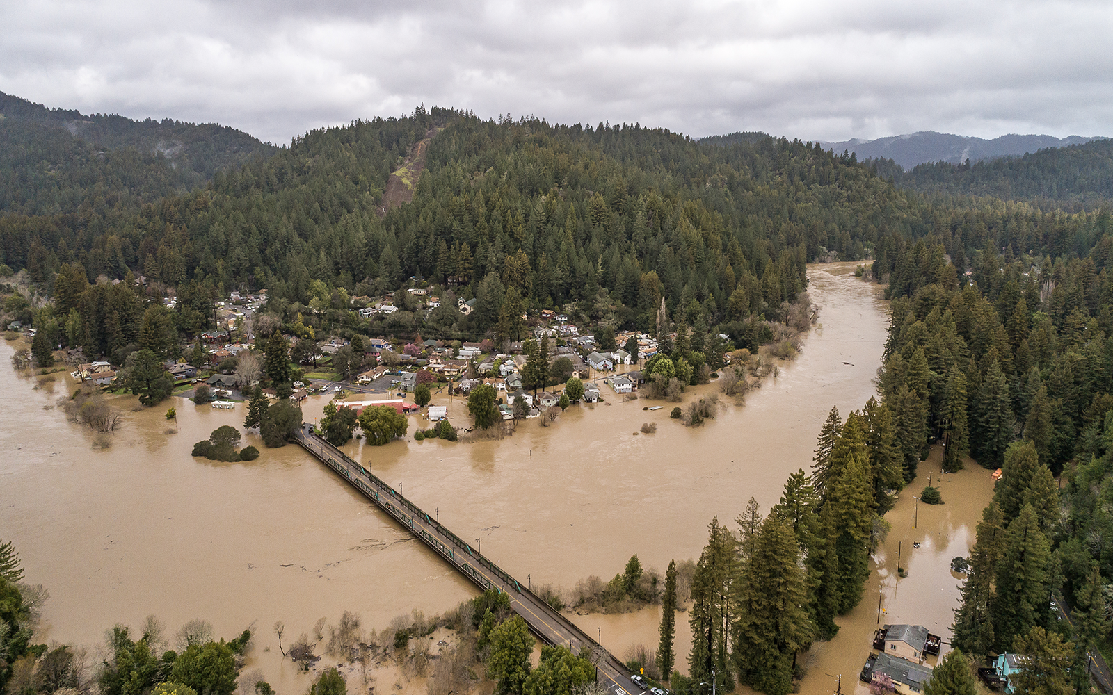 mountains and a bridge over brown water