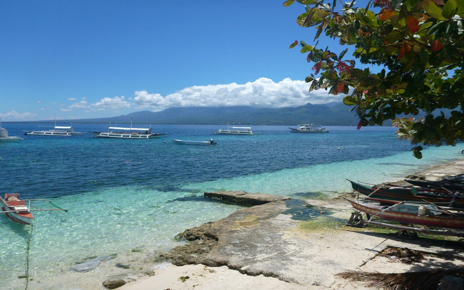 A coral reef in blue water with boats on it