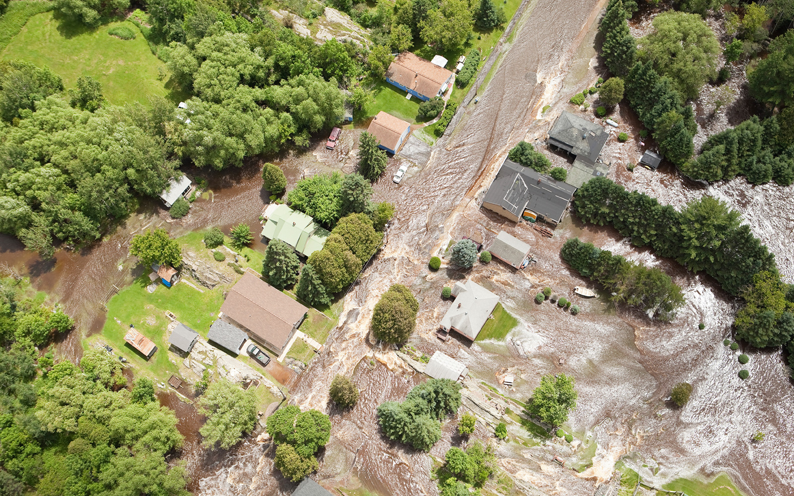 Aerial view of flood waters surging through local area with residential streets and homes.