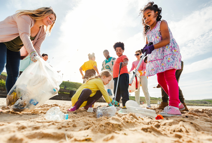 photo of children picking up plastic trash on a beach